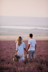 Loving couple admires the beautiful sunset in the lavender field. The guy and the girl are standing...