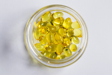 Yellow transparent pills in a glass jar on a white background. Medical concept.