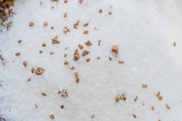 Extreme closeup of sugar and coffee granules from bag of coffee mix poured into a small bowl.