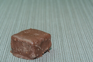 Single piece of dark chocolate confectionery on blue textured background.