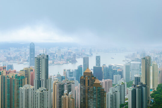 Monsoon fog descending on Hong Kong central district, with high rise business and residential buidlings along the river, from Victoria Peak in Hong Kong, China
