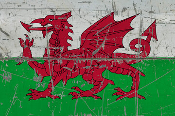 Wales flag painted on cracked dirty surface. National pattern on vintage style surface. Scratched and weathered concept.