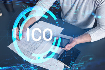 Multiexposure of man signing contract with phone and ico hologram. Concept of initial coin...
