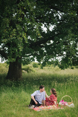 Happy couple sits has mini picnic near the big tree. Non alcoholic picnic