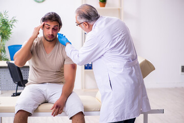 Fototapeta premium Young face injured man visiting experienced male doctor traumato
