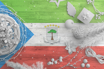 Equatorial Guinea flag on wooden table with snow objects. Christmas and new year background, celebration national concept with white decor.