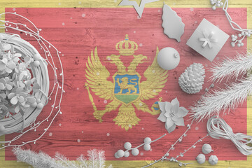 Montenegro flag on wooden table with snow objects. Christmas and new year background, celebration national concept with white decor.