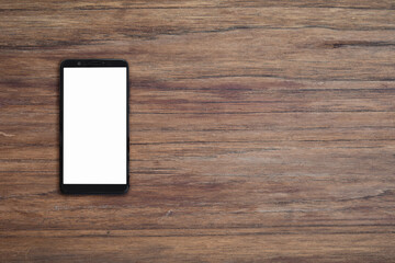 Mobile smartphone with blank screen on wood desk background with copy space. Top down