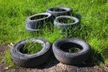 A pile of old car tires on a background of green grass.