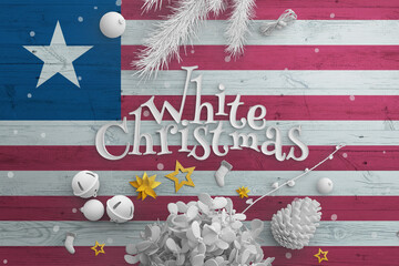 Liberia flag on wooden table with White Christmas text. Christmas and new year background,...