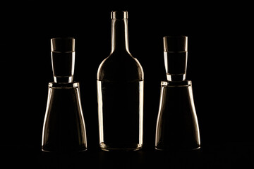 Abstract still life with glass objects with contour lighting. a bottle and glasses of alcohol are stacked on top of each other