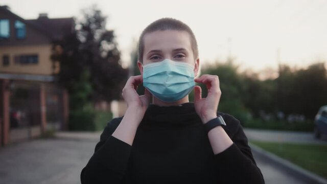 short haired young bald adult woman wearing protective facial mask on face on street. Coronavirus outbreak prevention. lgbt pride, lesbian happy girl