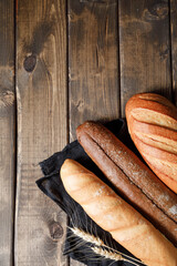 Variety of loaves of bread and baguette on wooden table background