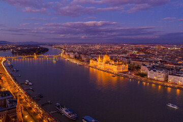 Aerial drone of lighted Hungarian Parliament by Danube river in Budapest sunset hour