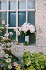 bridal bouquet of rose and cream roses and calla lilies on the window with bars near the flower pots