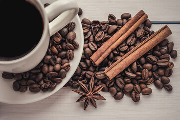 cup of coffee on a white wooden surface with cinnamon sticks top view