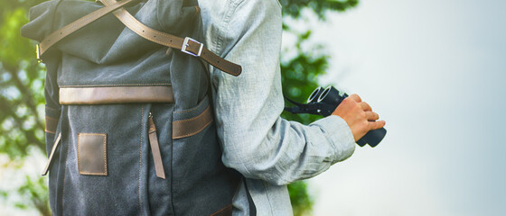 Traveller with backpack and binoculars on green nature background