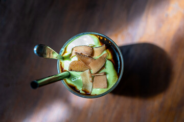 Green avocado smoothie with black coffee and coconut chips in a Vietnamese restaurant, close up, top view