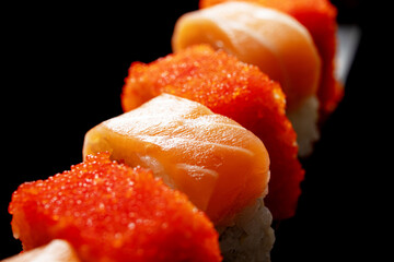 Japanese rolls and seafood sushi on a katana sword on a black background