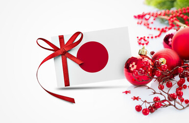 Japan flag on new year invitation card with red christmas ornaments concept. National happy new year composition. - Powered by Adobe