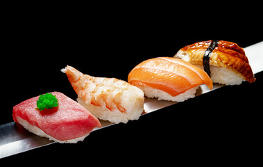 Japanese rolls and seafood sushi on a katana sword on a black background