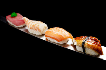 Japanese rolls and seafood sushi on a katana sword on a black background