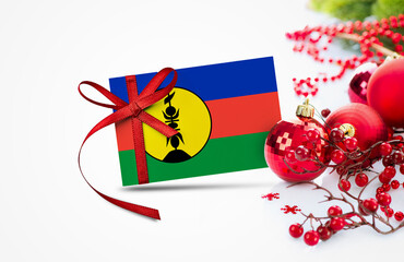 New Caledonia flag on new year invitation card with red christmas ornaments concept. National happy new year composition.