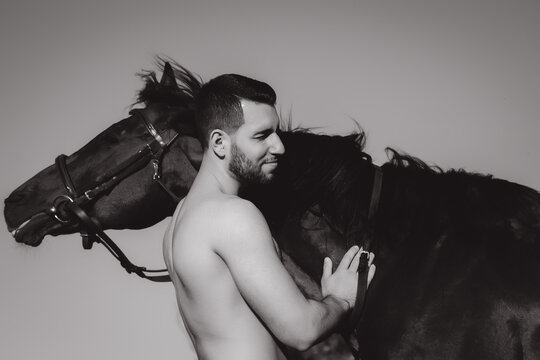 Young stylish man hugs his horse and smiles.