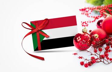 Sudan flag on new year invitation card with red christmas ornaments concept. National happy new year composition.