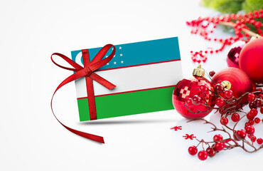 Uzbekistan flag on new year invitation card with red christmas ornaments concept. National happy...