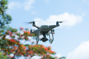 White drone with camera flying in summer