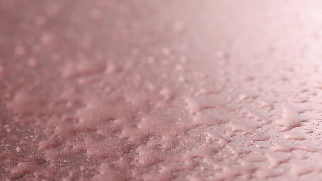 Copper. Drops of water are sprayed onto copper coating. Copper oxidation process. Chemical reaction a copper plate interacts with an oxidizing agent. Slow motion. 