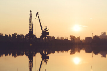 The silhouettes of port cranes against the sky.
