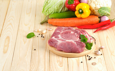 Pork neck Slice on wooden plate on wooden table with vegetables on background