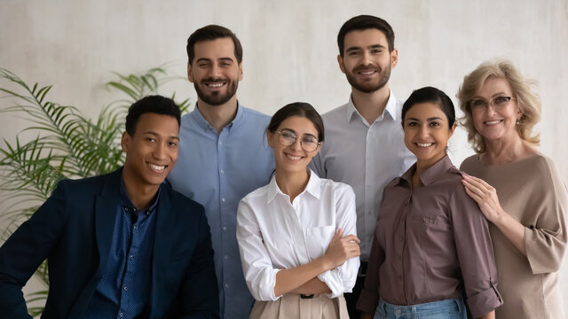Diverse happy business people successful employees team posing in office, looking at camera, smiling workers group, motivated staff, confident businesswomen and businessmen corporate portrait