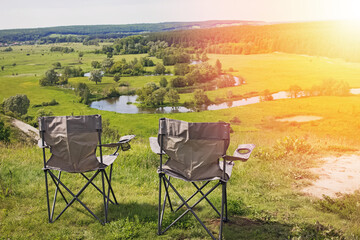 Two camping chairs standing on a hill with a beautiful view