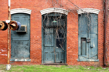 an abandoned old train depot building front with boarded up door and windows