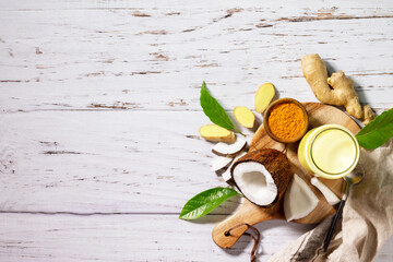 Cup of Healthy ayurvedic drink golden coconut milk turmeric iced latte with curcuma powder on kitchen table. Top view flat lay background. Copy space.