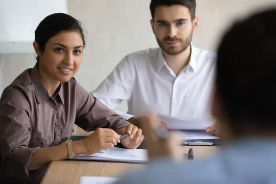 Diverse employees attentively listening to team leader at meeting, staff training concept, business partners discussing strategy in boardroom, two hr managers holding job interview with candidate