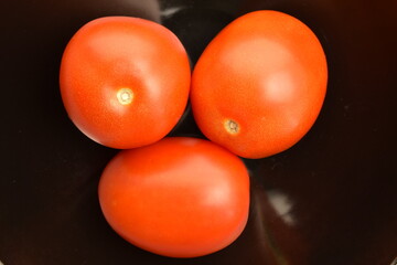 Red plum tomato, macro isolated on a black background.