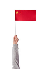 Children's hand holds the flag of China isolated on white background. Red flag with stars. Vertical frame
