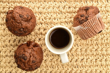 Chocolate muffins on a mat woven from straw, close-up.
