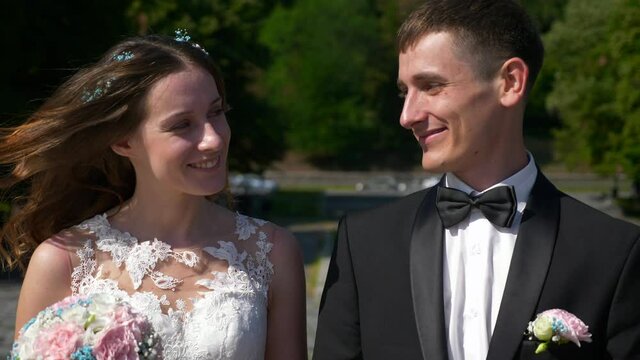 Bride and Groom Walk in Park Looking at Each Other. Urban Scene. Slow motion