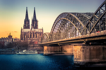 Cologne, Germany - UNESCO Cathedral in Cologne Germany and Hohenzollern Bridge across Rhine River with Boat at Evening Sunset