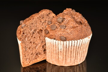 Halved chocolate muffin, close-up, on a black background.