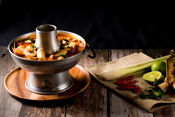 A delicious seafood soup of Thai people in a hot pot on a black background. Seafood Tom Yum with Coconut Milk