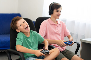 Teenager plays a computer game with headphones and a joystick, game console.