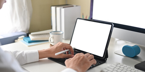 Cropped image of a businessman is using a white blank screen computer tablet at the white working desk.