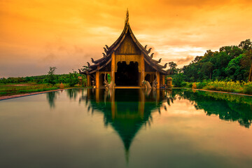 Naklejka premium The background of the Wat Pa Kham Charoen is a beautiful old church with a Buddhist statue and a tree-lined temple, with tourists and travelers always making merit in Udon Thani, Thailand.