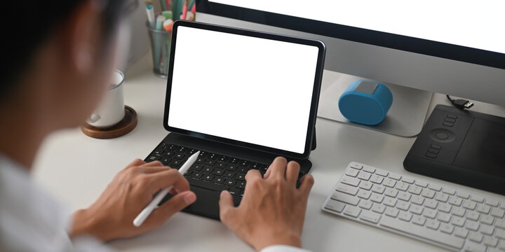 Cropped image of a businessman is using a white blank screen computer tablet at the white working desk.